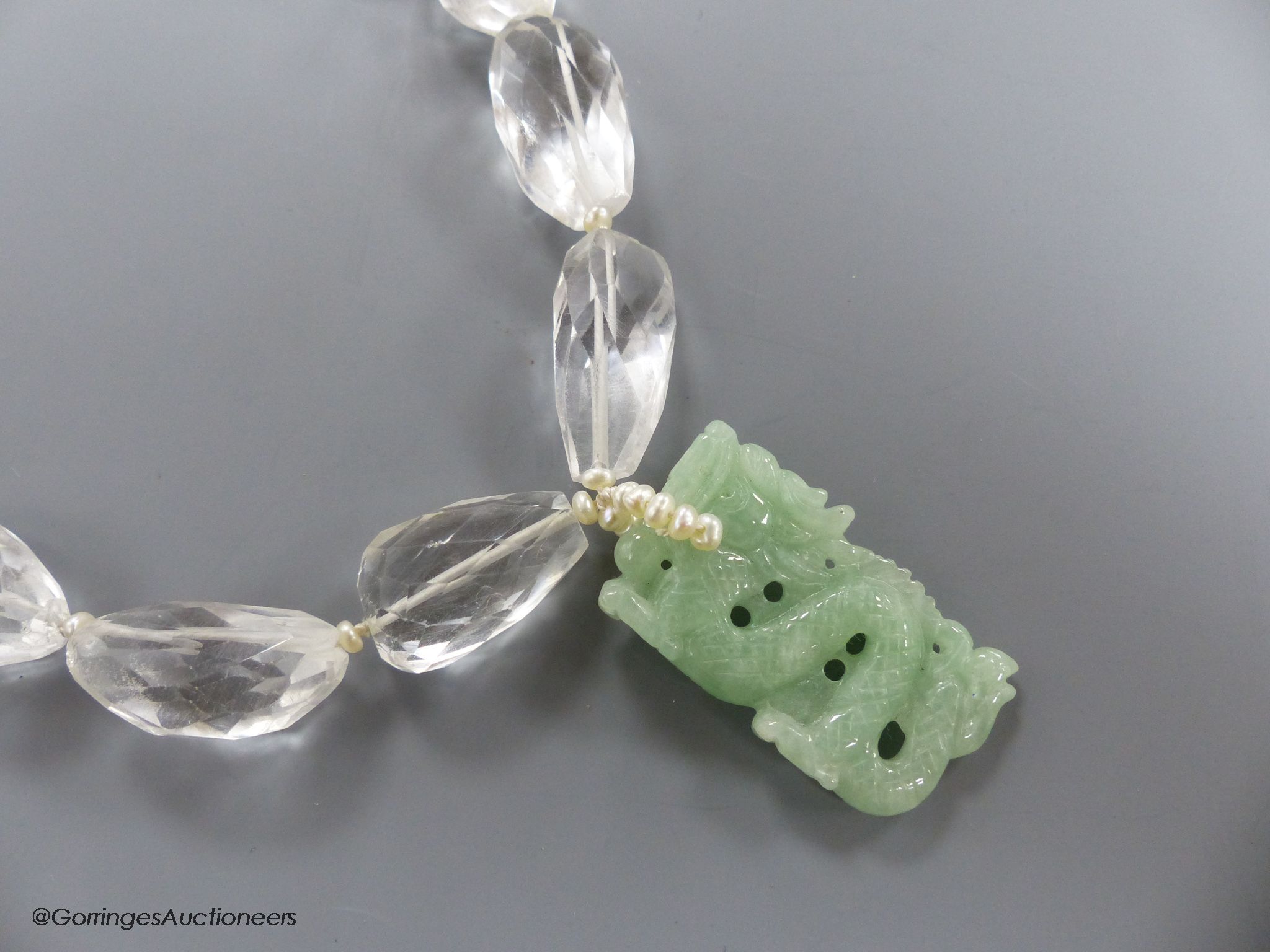 A shaped facet cut rock crystal necklace, with carved jade pendant, seed pearl bale and white metal clasp, necklace approx. 43cm, pendant 36mm, gross weight 97 grams.